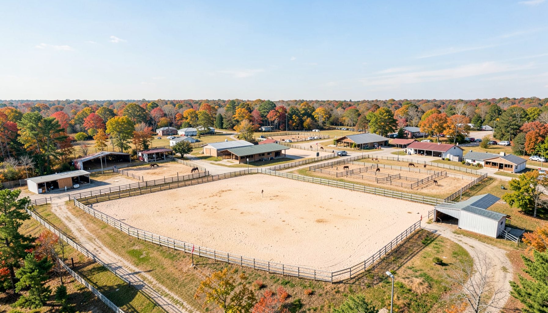 Wide aerial view of the Gov. James B. Hunt Jr. Horse Complex show grounds on a bright autumn afternoon, with several outdoor arenas and barns spread across the property